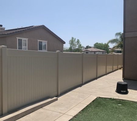 A wooden fence stands in front of a house, creating a boundary around the property.