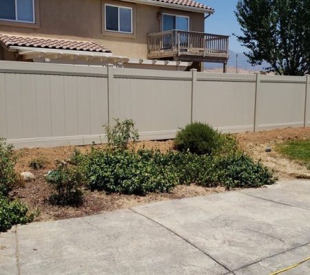 A construction worker builds a wooden fence in front of a house, partially obscuring the view of the home.
