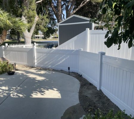 A white fence stands in front of a house, framing the property and enhancing its curb appeal.