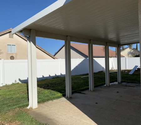 A covered patio featuring a white fence and a white roof, providing a shaded outdoor space.
