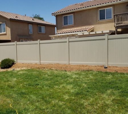 A wooden fence is installed in front of a house, providing privacy and defining the property boundary.