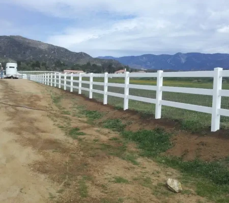 Rural landscape featuring a dirt road, a white picket fence, a white house, and a parked truck under a blue sky with white clouds.