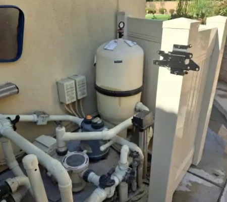A residential water system featuring a white water tank with a black top, gray water pipe, and gray water valve on a beige wall.